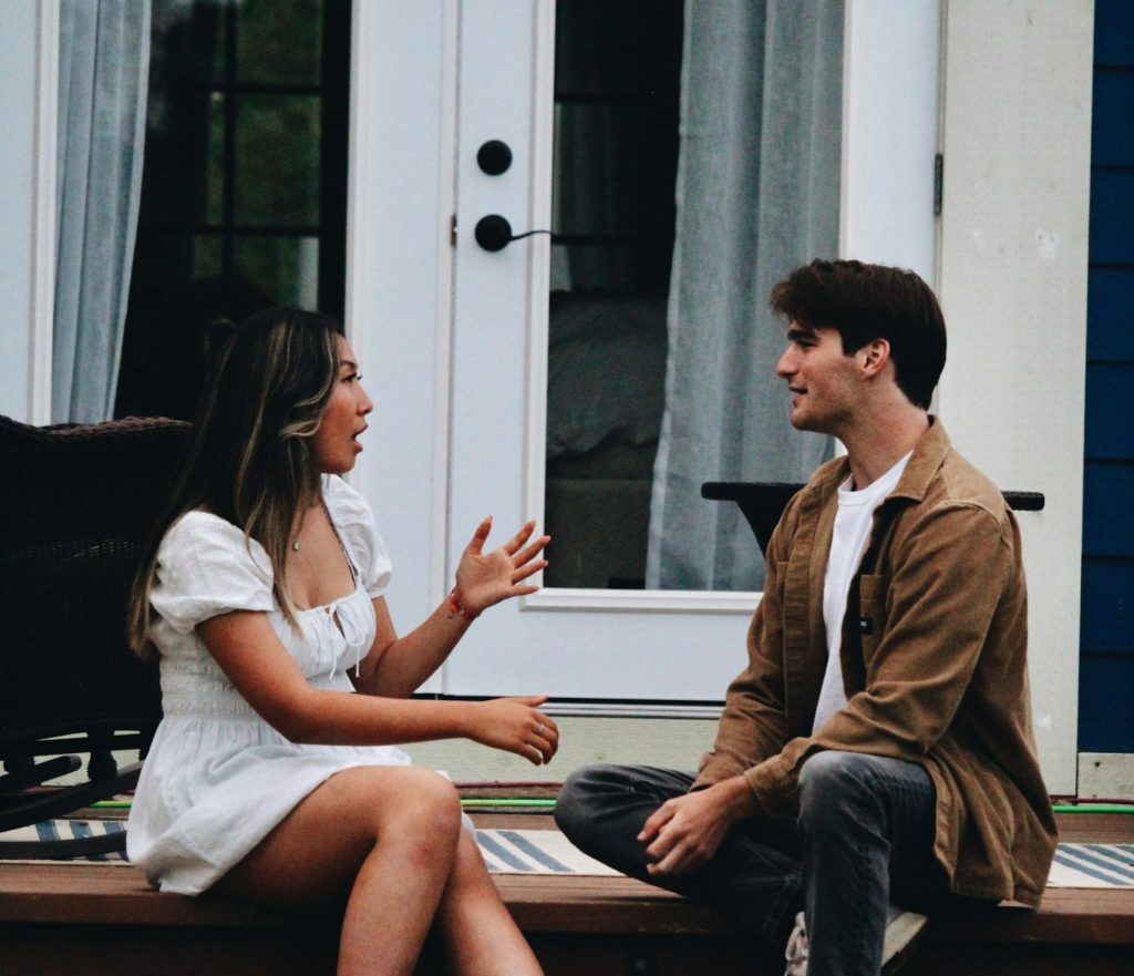 Two people sitting on the deck engaging in conversation.